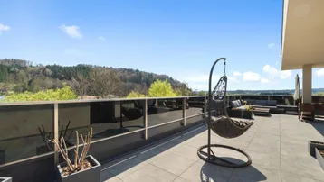 Große Dachterrasse mit Hängesessel und weitem Blick über die Landschaft.