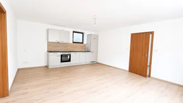 Heller Raum mit neuer Einbauküche, hellem Laminatboden und weißen Wänden, ideal für offenes Wohnen.