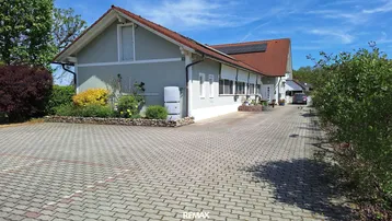 Seitenansicht des Gebäudes mit gepflasterter Auffahrt und begrüntem Vorgarten.