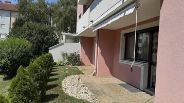 Kleine Terrasse mit gepflastertem Weg und einem gepflegten Gartenbereich neben dem Gebäude.