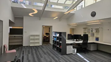 Großes, helles Großraumbüro mit Glasdach, modernen Arbeitsplätzen und viel Tageslicht.