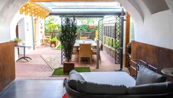 Überdachte Terrasse mit Essbereich, Lounge-Möbeln und direktem Zugang zum Garten.