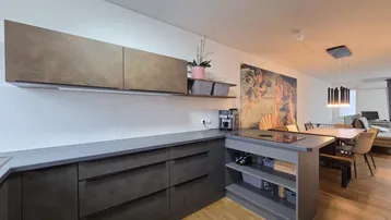 Moderne offene Küche mit dunklen Fronten, Kochinsel und angrenzendem Essbereich mit großem Wandbild.
