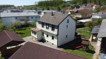 Luftaufnahme des Wohnhauses mit Satteldach, Garten und Spielplatz im ländlichen Umfeld.
