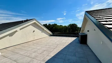 Großzügige Dachterrasse mit modernen Fliesen, weitem Blick und viel Sonnenlicht.