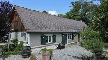 Traditionelles Landhaus mit Satteldach, grünen Fensterläden und einem Kiesweg im Vorgarten.