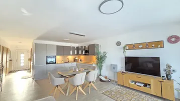 Heller offener Wohn-Essbereich mit moderner Küche, Esstisch und Zugang zum Wohnzimmer.