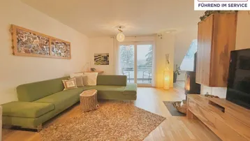 Gemütliches Wohnzimmer mit grünem Sofa, Holzboden und Kaminofen, der eine warme Atmosphäre schafft.