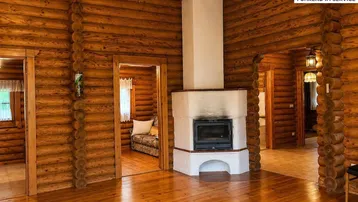 Gemütliches Wohnzimmer im Blockhausstil mit Holzbalkenwänden, Holzboden und einem zentralen Kamin.