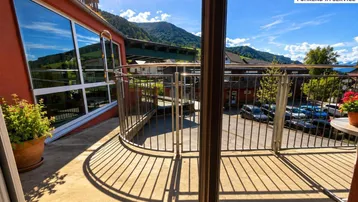Geräumiger Balkon mit Metallgeländer bietet einen weiten Blick auf die umliegende Berglandschaft und den Parkplatz.
