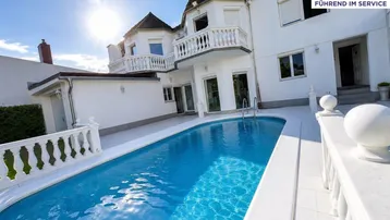 Elegante Villa mit privatem Pool und sonniger Terrasse, umgeben von klassischer Balustrade.