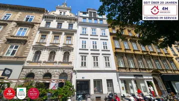 Historische Fassade eines Mehrfamilienhauses in einer belebten Stadtstraße mit moderner Architektur.