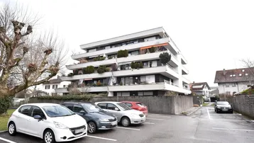 Mehrstöckiges Apartmentgebäude mit Balkonen und Außenparkplätzen in einer Wohngegend.