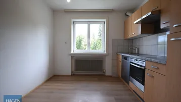 Küche mit Einbauschränken, Spüle, Herd und Fenster mit Blick ins Grüne, bereit zur Nutzung.