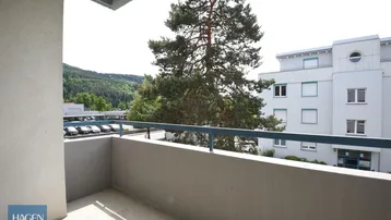 Balkon mit Blick auf die Umgebung und einen großen Baum, ideal zum Entspannen im Freien.