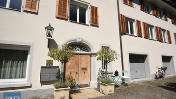 Historische Fassade eines Wohnhauses mit Holztüren, Fensterläden und Garagenzugängen.