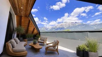 Heller, geräumiger Wohnbereich mit Eichenparkett, moderner Treppe und Zugang zu einem Balkon mit Bergblick.