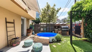 Sonniger Gartenbereich mit kleinem Pool, Grillplatz und gemütlicher Sitzecke für entspannte Stunden im Freien.