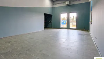 Großer, leerer Gewerberaum mit hohen Decken, Fliesenboden und zwei Fenstern, bereit zur Nutzung.
