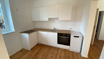 Neue Einbauküche mit weißen Fronten, Holzoptik-Arbeitsplatte und integrierten Geräten.