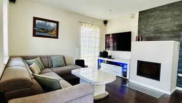 Gemütliches Wohnzimmer mit Kamin, Ecksofa und dunklem Holzboden.