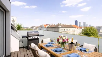 Geräumige Dachterrasse mit Esstisch, Grill und weitem Blick über die Stadt.