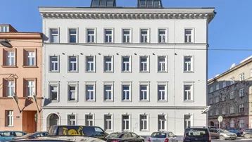 Klassische Fassade eines Mehrfamilienhauses mit vielen Fenstern und Dachgauben in städtischer Umgebung.