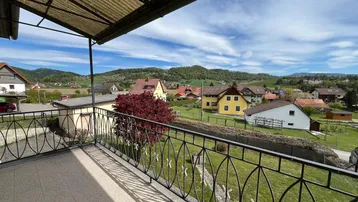 Geräumiger Balkon mit Blick auf die umliegende Landschaft und Häuser unter blauem Himmel.