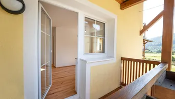 Heller Balkon mit Holzboden und Blick auf die umliegende Landschaft.