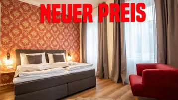 Schlafzimmer mit Doppelbett, rotem Sessel und auffälliger Tapete, hell beleuchtet.