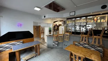 Gastraumbereich mit Bar, Tischen und Bänken, bereit für den Betrieb oder die Reinigung.
