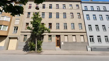 Mehrstöckiges Wohngebäude mit schlichter Fassade und vielen Fenstern an einer Stadtstraße.