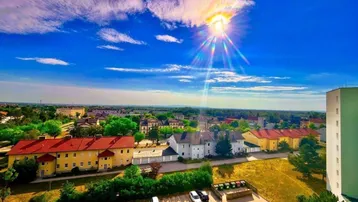 Panoramablick über die Stadt und die umliegende Landschaft unter strahlend blauem Himmel.