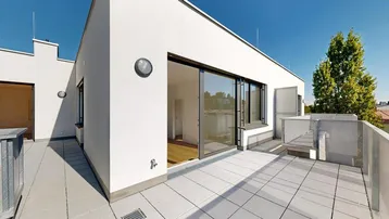Geräumige Dachterrasse mit hellen Fliesen und Zugang zu den Innenräumen unter blauem Himmel.