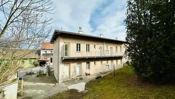 Mehrfamilienhaus mit mehreren Balkonen und einem gepflegten Vorgartenbereich.