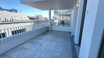 Geräumige Terrasse mit Fliesenboden und Blick auf die umliegenden Gebäude und Dächer.