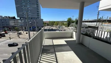 Geräumiger Balkon mit Fliesenboden und Blick auf die Stadt und die umliegende Infrastruktur.