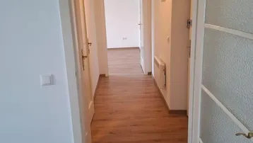 Heller Flur mit Laminatboden und Türen zu weiteren Zimmern in gutem Zustand.