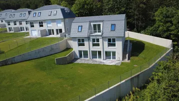 Neubau-Reihenhäuser auf einem Hanggrundstück mit frisch angelegten Rasenflächen und moderner Architektur.