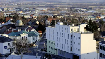 Panoramablick über eine Stadt mit einem modernen Wohngebäude und umliegender Landschaft.
