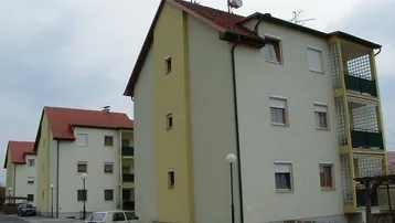 Mehrere Mehrfamilienhäuser mit hellen Fassaden, roten Ziegeldächern und Balkonen in einer Wohnsiedlung.