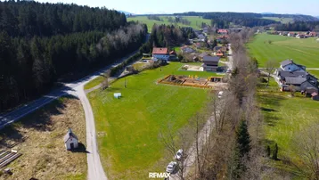 Luftaufnahme eines weitläufigen Grundstücks mit angrenzendem Wald und ländlicher Umgebung, ideal für Neubauprojekte.