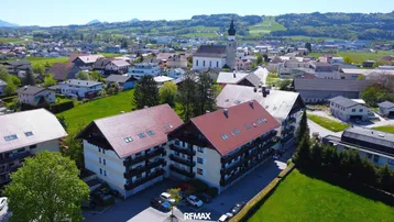 Luftaufnahme eines Wohnkomplexes mit roten Dächern und grüner Umgebung in einer ländlichen Gegend.