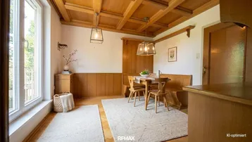 Gemütlicher Essbereich mit Holzbalkendecke, Holzvertäfelung und großem Fenster für viel Tageslicht.