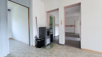 Wohnzimmer mit hellem Bodenbelag und einem modernen Holzofen.
