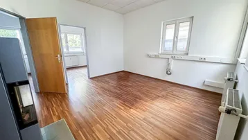 Geräumiges Büro mit hellem Holzfußboden, weißen Wänden und einem modernen Kaminofen.