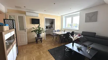 Geräumiger Wohn-Essbereich mit Parkettboden, bequemer Couch und integrierter Essecke, ideal für geselliges Beisammensein.