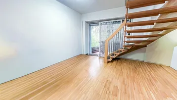 Heller Wohnbereich mit Holztreppe, Parkettboden und Schiebetür zum Außenbereich.