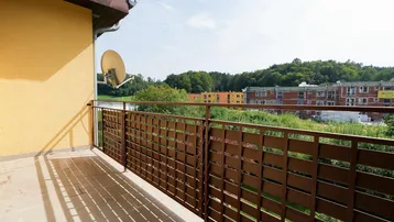 Balkon mit Gittergeländer und Blick auf die grüne Umgebung und Neubauten.