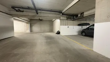 Geräumige Tiefgarage mit Betonboden und markierten Parkplätzen für Fahrzeuge.